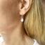     Woman wearing a dainty pear shaped moonstone drop earring with delicate gold filled ear wire