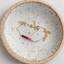 Gold-filled ombré ruby necklace coiled in a speckled ceramic dish