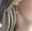 Close-up of a gold hoop earring with an opal charm