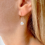 White opal teardrop earrings worn on ear with gold-filled hook