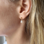 Gold opal teardrop drop stud earring worn on the ear