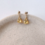 Gold filled citrine drop stud earrings resting on the edge of a ceramic dish