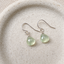 Prehnite heart drop earrings in sterling silver on a speckled ceramic dish