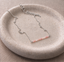 Sterling silver pink opal beaded bar necklace on a speckled ceramic dish