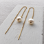 Gold filled freshwater pearl threader earrings with cable chain and threader bar resting on a textured white plaster board