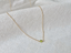 Gold filled tiny peridot bead necklace draped on linen