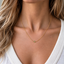 Dainty gold peridot bead necklace layered with a white V-neck in natural light