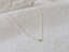 Sterling silver tiny peridot bead necklace draped on linen