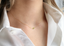 Tiny peridot necklace worn with an open-collar white button-down shirt
