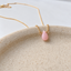 Close-up of a wire-wrapped pink opal briolette on a speckled ceramic dish