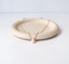 Pink opal teardrop necklace laid across a speckled dish