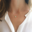 Model wearing a dainty prehnite necklace in 14k gold-filled with a white blouse
