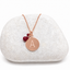 Rose gold-filled initial disc necklace stamped with A and genuine ruby charms on a white stone