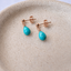 Turquoise teardrop stud earrings in rose gold filled with ball posts on a ceramic dish