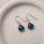 London blue topaz dangle earrings in 14k rose gold filled on a speckled ceramic dish