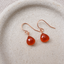 Carnelian heart drop earrings in 14k rose gold-filled on a speckled ceramic dish