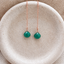 Emerald threader earrings in rose gold filled with faceted emerald briolette drops on a fine chain, on a speckled ceramic dish