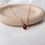 Garnet teardrop necklace in 14k rose gold-filled on a stone dish