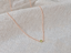 Rose gold filled tiny peridot bead necklace draped on linen
