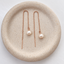 Dainty pearl threader earrings in 14k rose gold filled with a wire-wrapped freshwater pearl on a cable chain, in a speckled ceramic dish