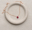 Ruby teardrop necklace in 14k rose gold-filled on a speckled ceramic dish