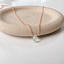 Prehnite teardrop necklace in 14k rose gold-filled on a stone dish