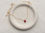 Dainty ruby teardrop necklace in 14k gold-filled with a faceted red ruby briolette on a speckled ceramic dish