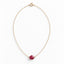 A dainty red ruby hangs from a delicate gold cable chain