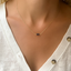 Necklace with small beads worn by a model in a white sweater.