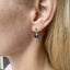 Model wearing dainty blue sapphire teardrop stud earrings with gold settings.