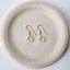 Pair of gold-filled prehnite drop earrings centered on a round speckled ceramic plate