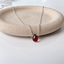 Garnet teardrop necklace in sterling silver on a stone dish