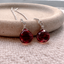 Sterling silver garnet threader earrings with faceted garnet drops on a stone dish