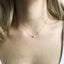 Close up of dainty 14k gold filled mother of pearl necklace worn on neck