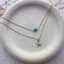 Dainty 14k gold filled single turquoise round gemstone necklace layered with a gold starfish charm necklace on ceramic dish
