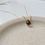 Faceted smoky quartz teardrop pendant on a gold-filled chain on a ceramic dish