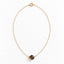 A faceted dainty smoky quartz gemstone hangs from a dainty gold filled cable chain displayed on a white background 