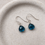 London blue topaz dangle earrings in sterling silver on a speckled ceramic dish