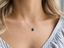 Model wearing a dainty London blue topaz teardrop necklace at the collarbone with a striped blouse