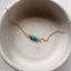 December birthstone turquoise bead necklace draped in a speckled ceramic bowl