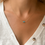 Model wearing a dainty turquoise three-bead necklace in 14k gold-filled at the collarbone with a white cardigan