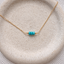 Turquoise three-bead necklace in 14k gold-filled with three faceted turquoise rondelles on a dainty cable chain, on a speckled stoneware dish