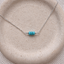 Turquoise three-bead necklace in sterling silver with three faceted turquoise rondelles on a dainty cable chain, on a speckled stoneware dish