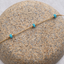 Gold-filled turquoise station bracelet draped over a speckled stone