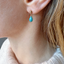 Turquoise teardrop stud earring worn with a cream sweater, December birthstone