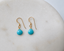 Pair of gold filled turquoise dangle earrings on a white marble tray