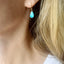 Woman wearing a dainty turquoise teardrop earring with delicate gold filled ear wire