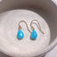 Close up of turquoise teardrop earrings showing bright blue gemstones and gold filled ear wires