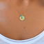Close-up of a gold filled initial disc with a faceted turquoise teardrop worn on the collarbone