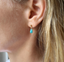 Woman wearing a dainty gold filled turquoise teardrop stud earring